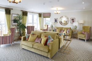 lounge area with green sofas, colourful pillows and sofa chairs